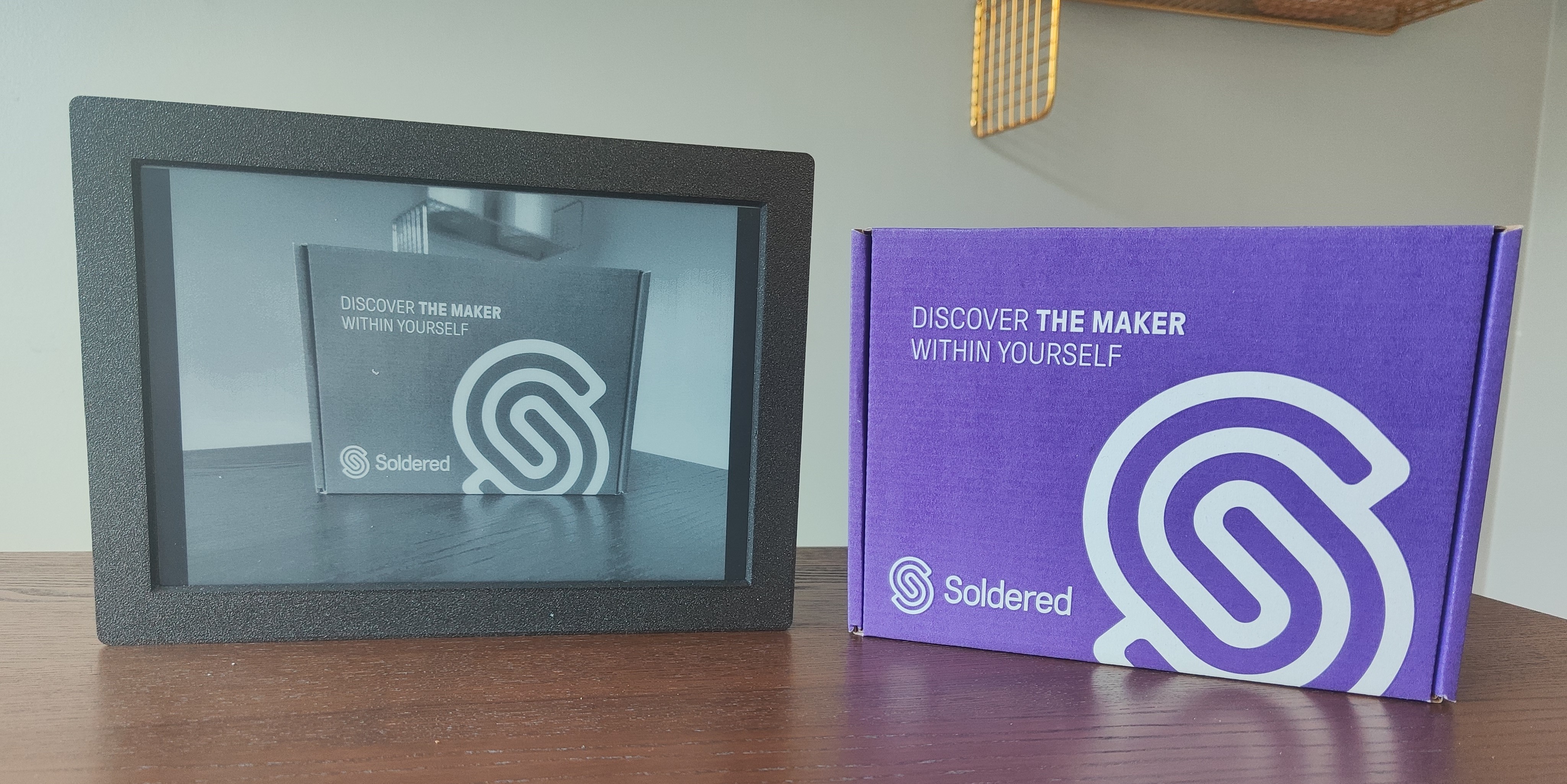 Inkplate 10 e-paper display in a black frame showing a greyscale photo, next to a Soldered box