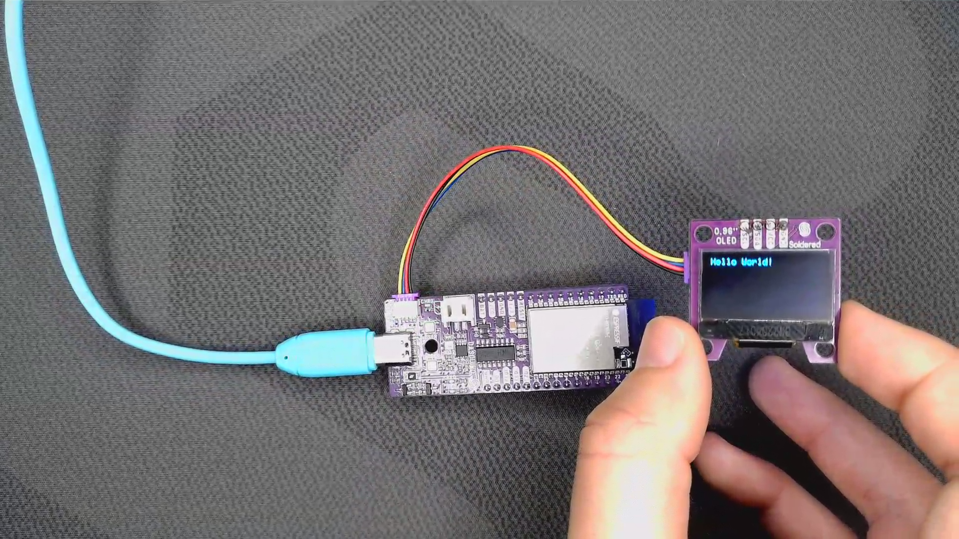 Small OLED display showing Hello World, connected to a NULA board with a Qwiic cable